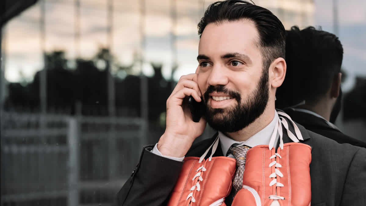 businessman suit talking his mobile phone with red boxing gloves hanging from his neck leaning
