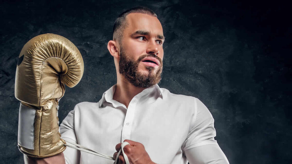 cheeky handsome in man white shirt with golden boxing glove is standing | dark studio | magnific | 26605858